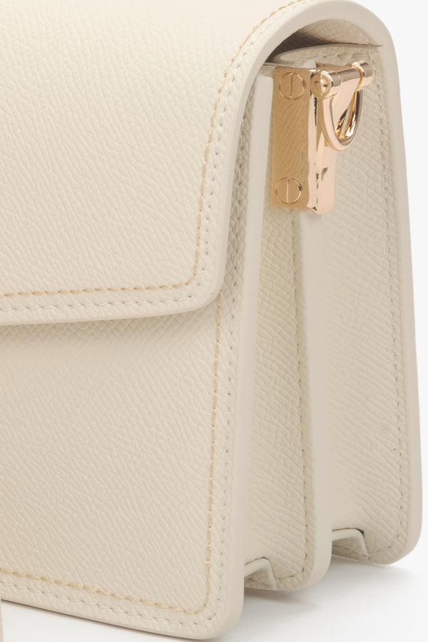 Compact off-white leather bag with a functional zipper and adjustable shoulder strap.