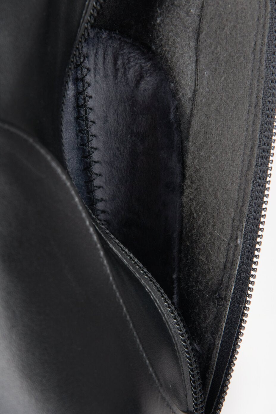 Black leather knee-high heeled boots - a close-up on fastening.