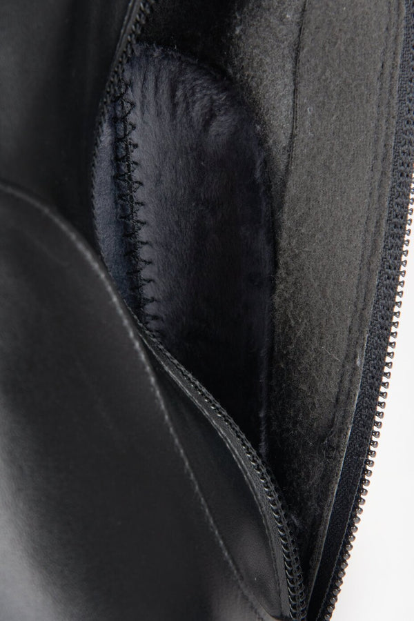 Black leather knee-high heeled boots - a close-up on fastening.
