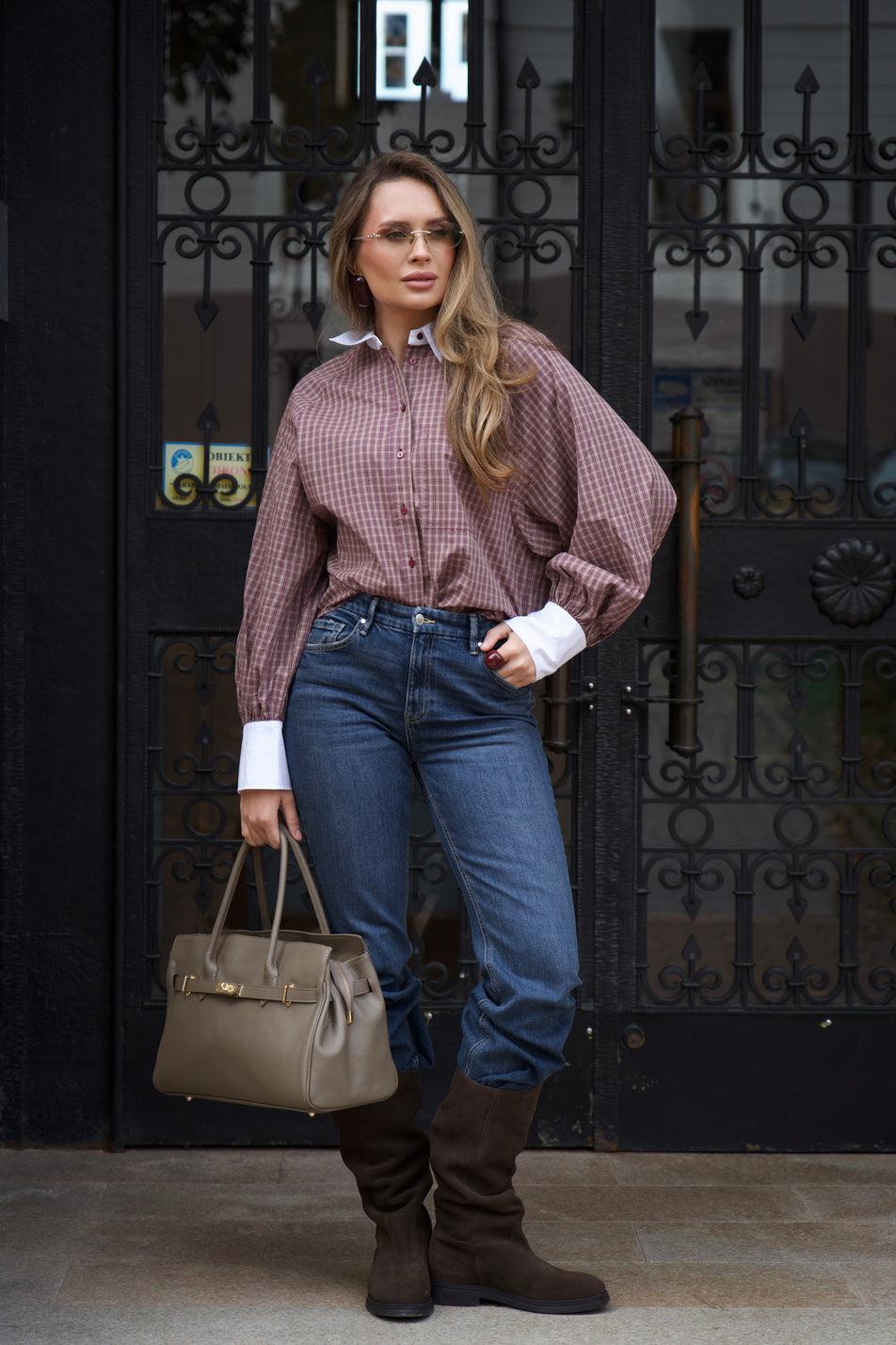 Women's large brown genuine leather bag Estro - full-length lifestyle shot with a model sitting on steps.