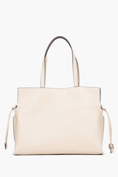 Close-up of a beige bag featuring adjustable side drawstrings that elegantly gather the sides and transform the silhouette of the bag.
