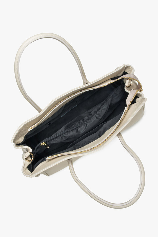 The bag styled with both the short handle and longer strap, demonstrating versatile hand and shoulder carrying options.