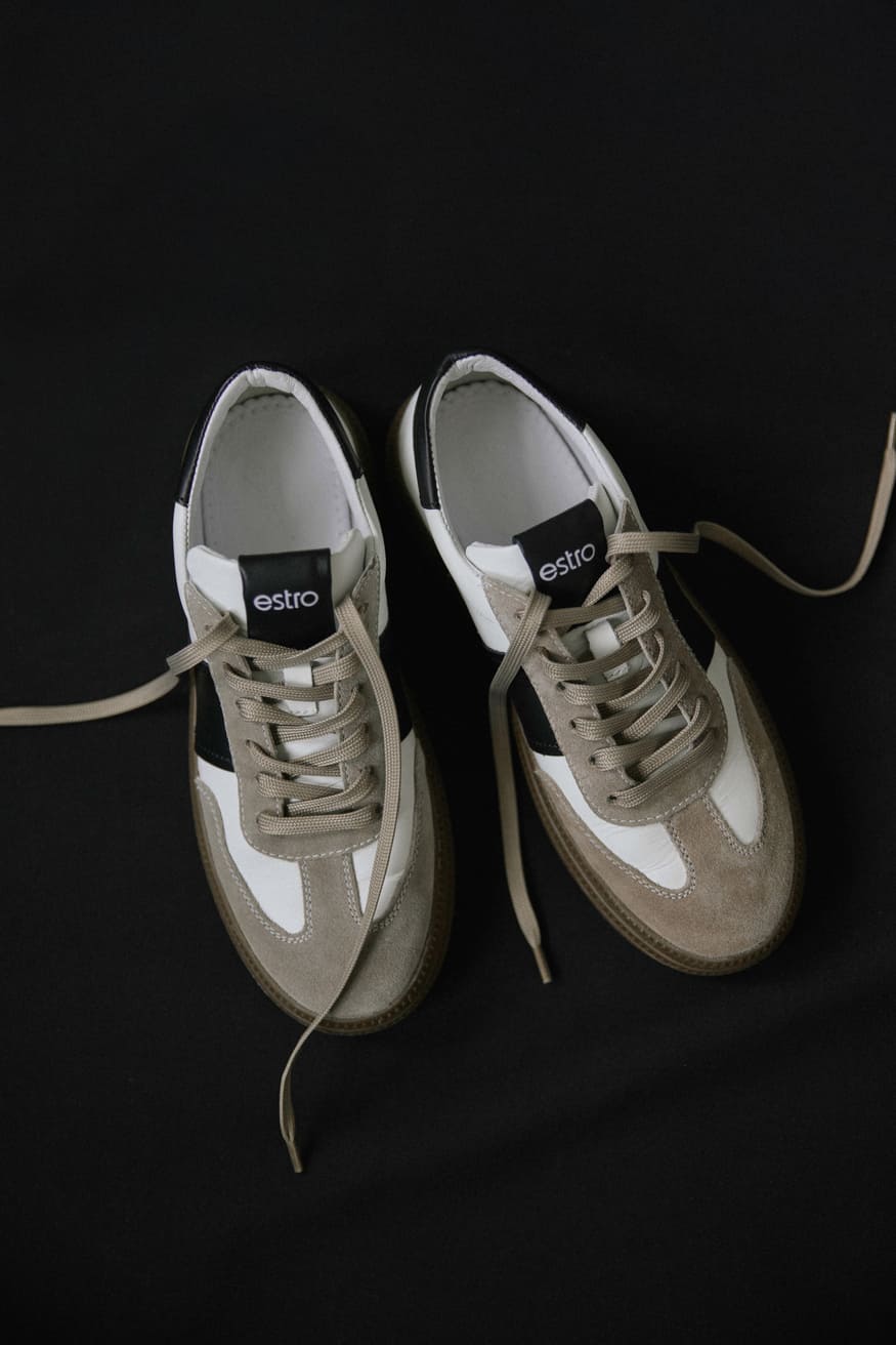 White and gray sneakers made of natural leather and velour - presentation from above on a black background.