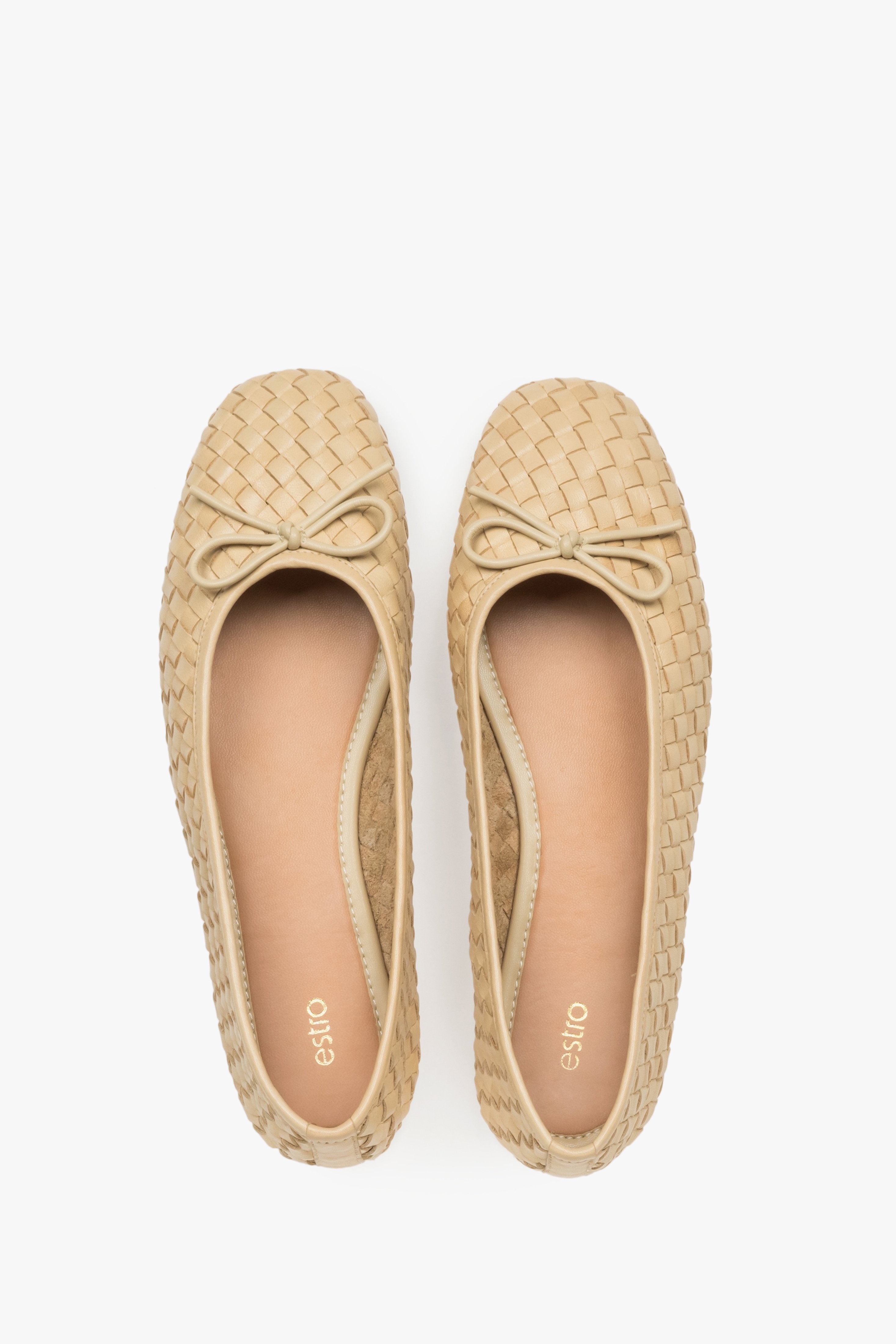 View of a pair of shoes, showcasing a neat round toe with a decorative bow and a smooth leather insole.