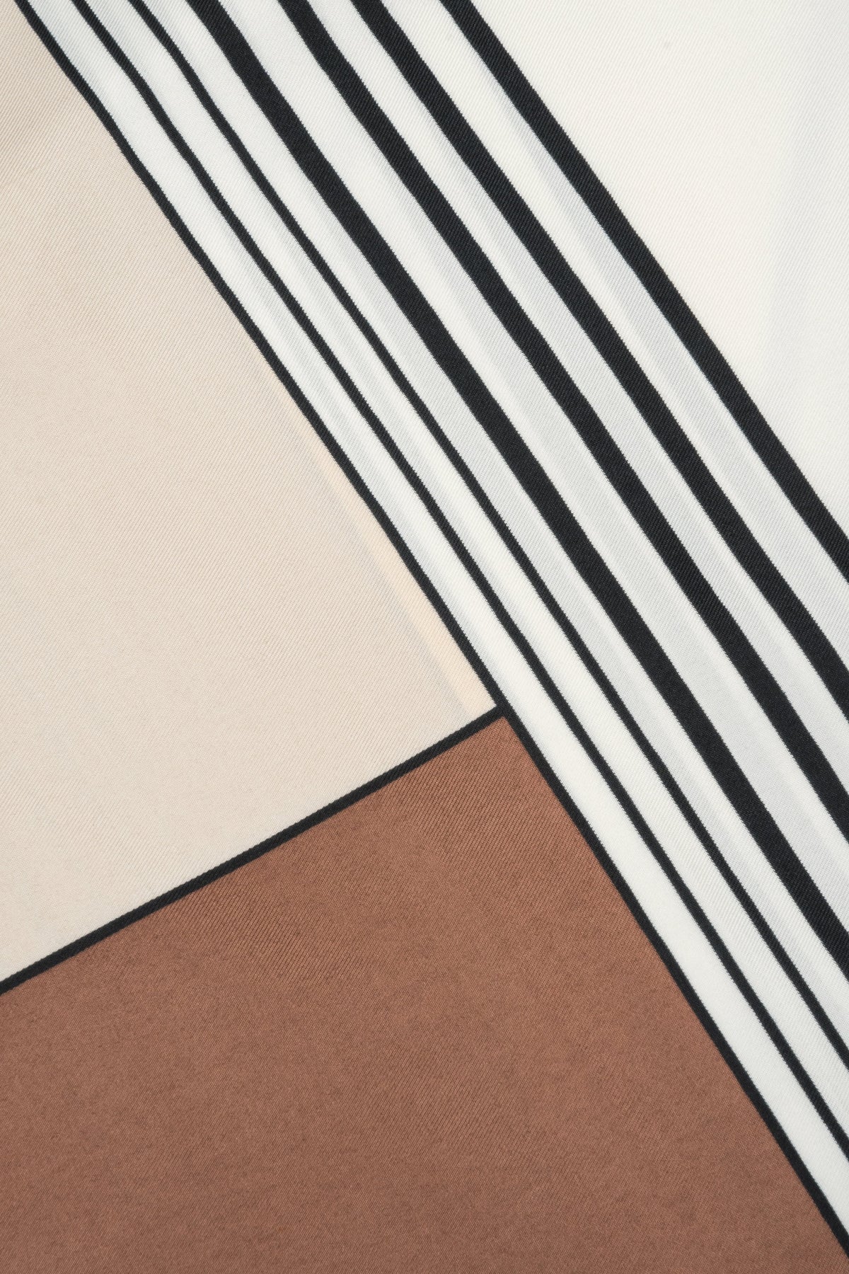Women's light beige, brown, and black scarf with abstract pattern: close-up of details.