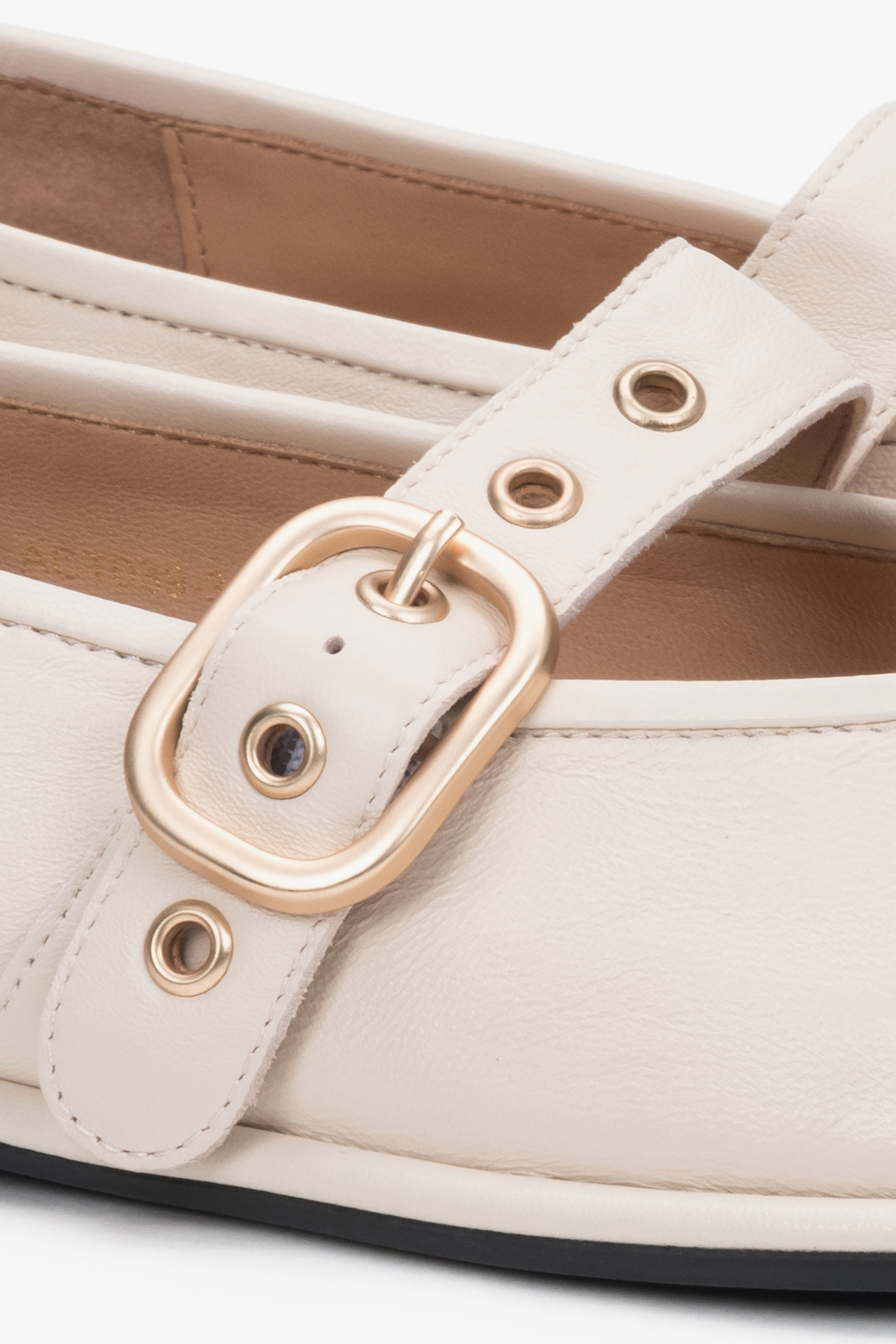 A close-up shot focusing on the high-quality, smooth milky beige leather texture and the polished brilliance of the golden buckle closure.