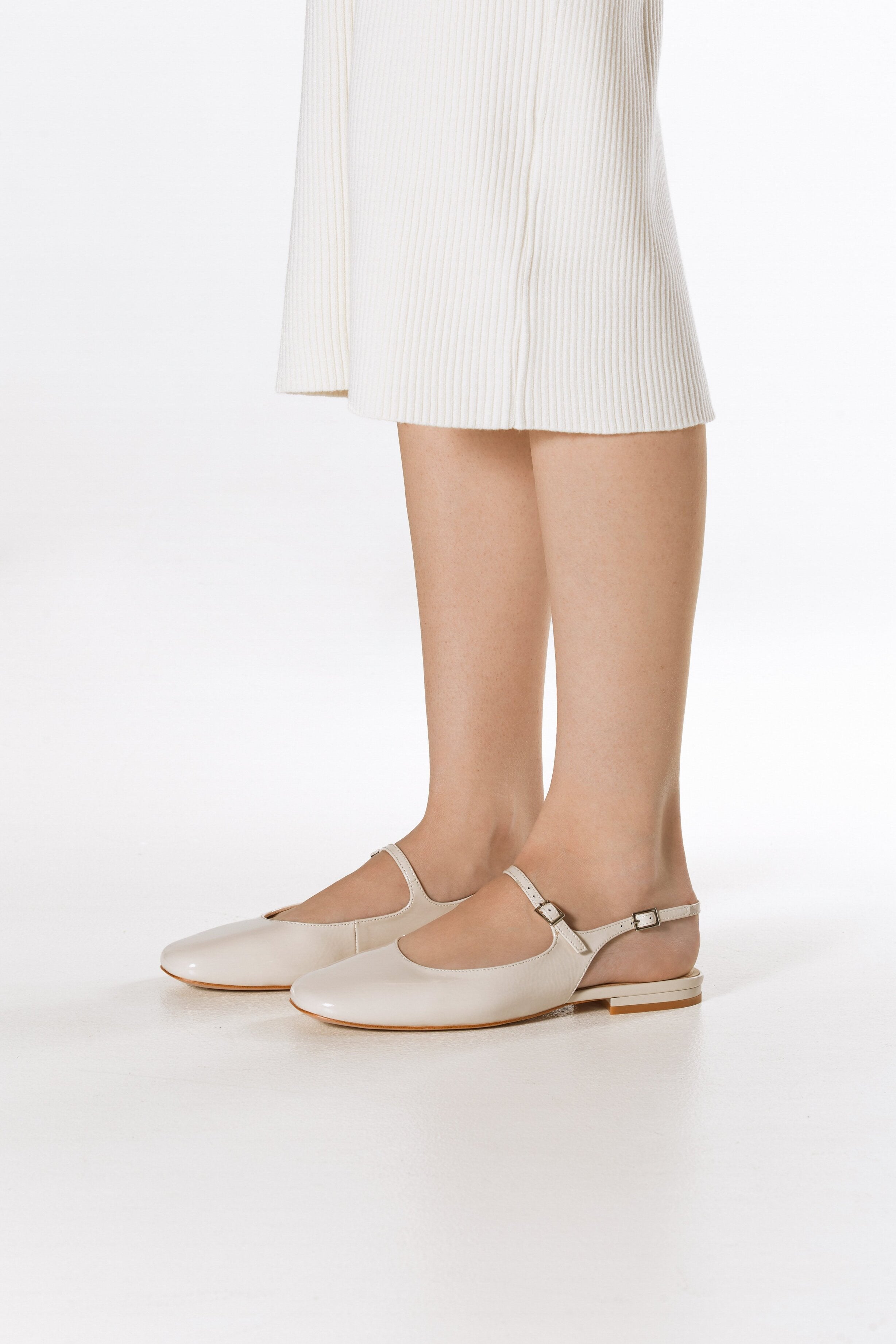 Women's light beige patent leather flats with slingback strap - presentation of the shoes on the foot.