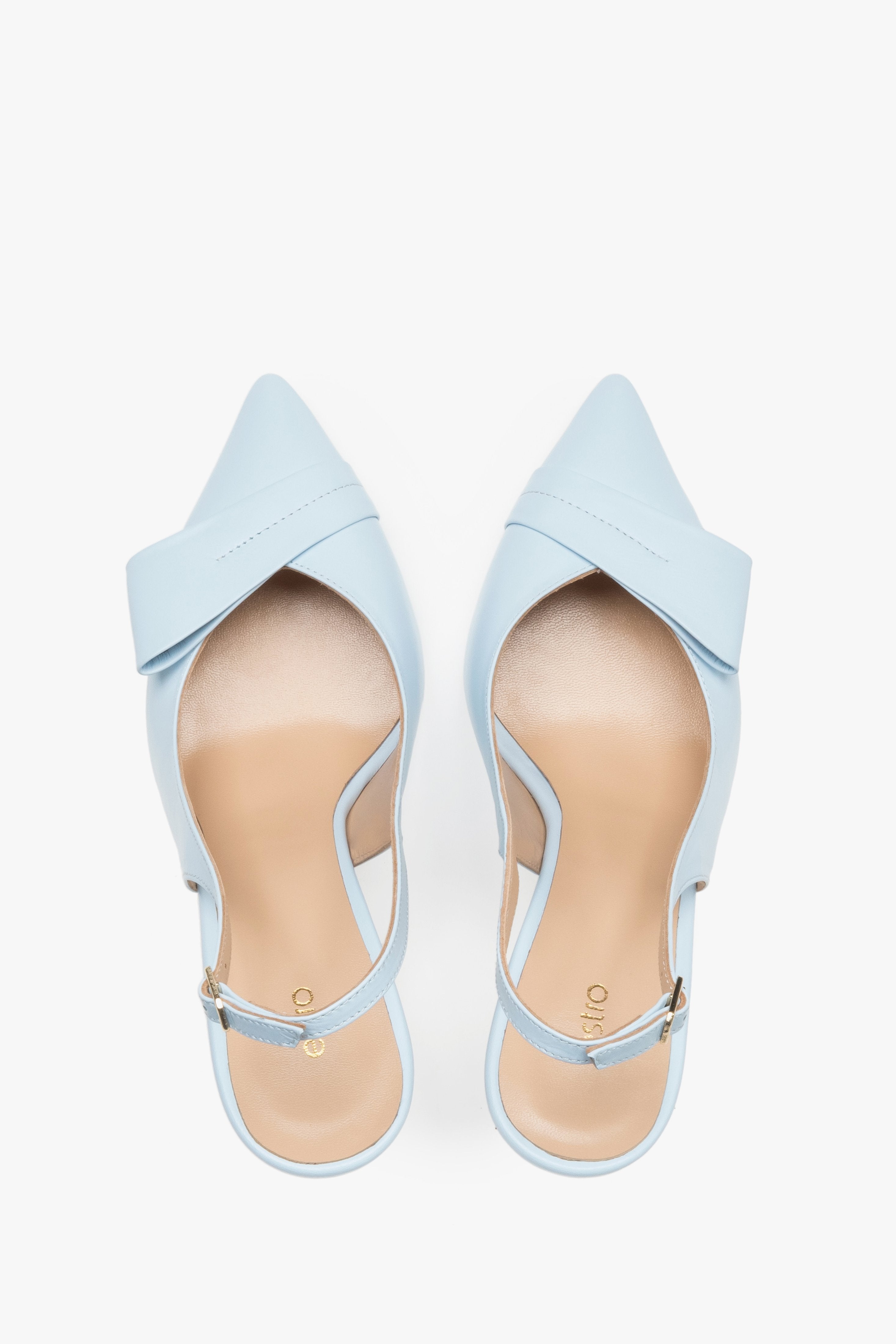 Top view of a pair of light blue pumps, showcasing a sharp pointed toe, an applied leather buckle detail, and a smooth natural leather insole featuring the brand logo.