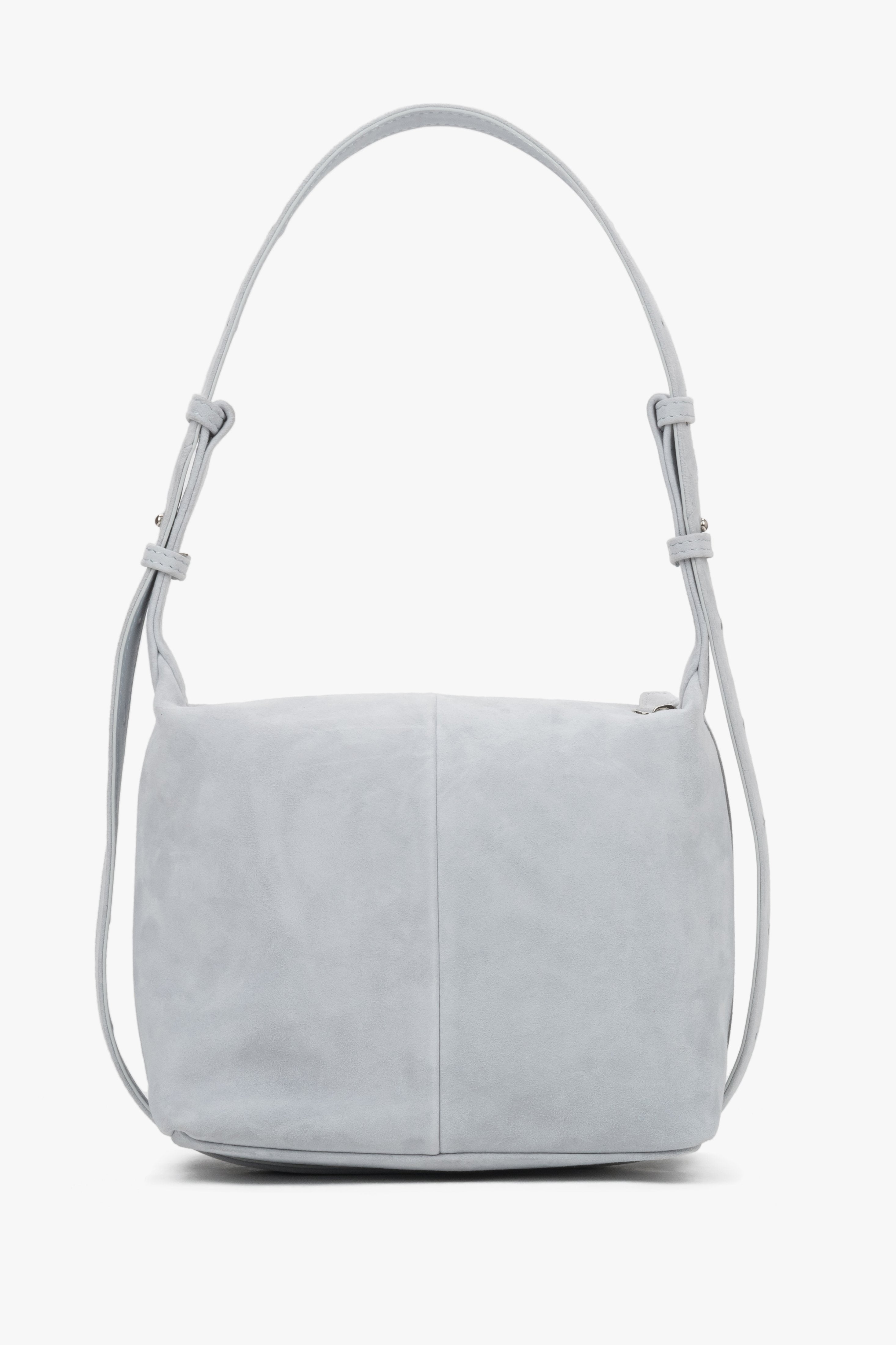 Light blue natural suede handbag, showing a smooth back with a vertical center seam and aesthetically finished strap attachments.