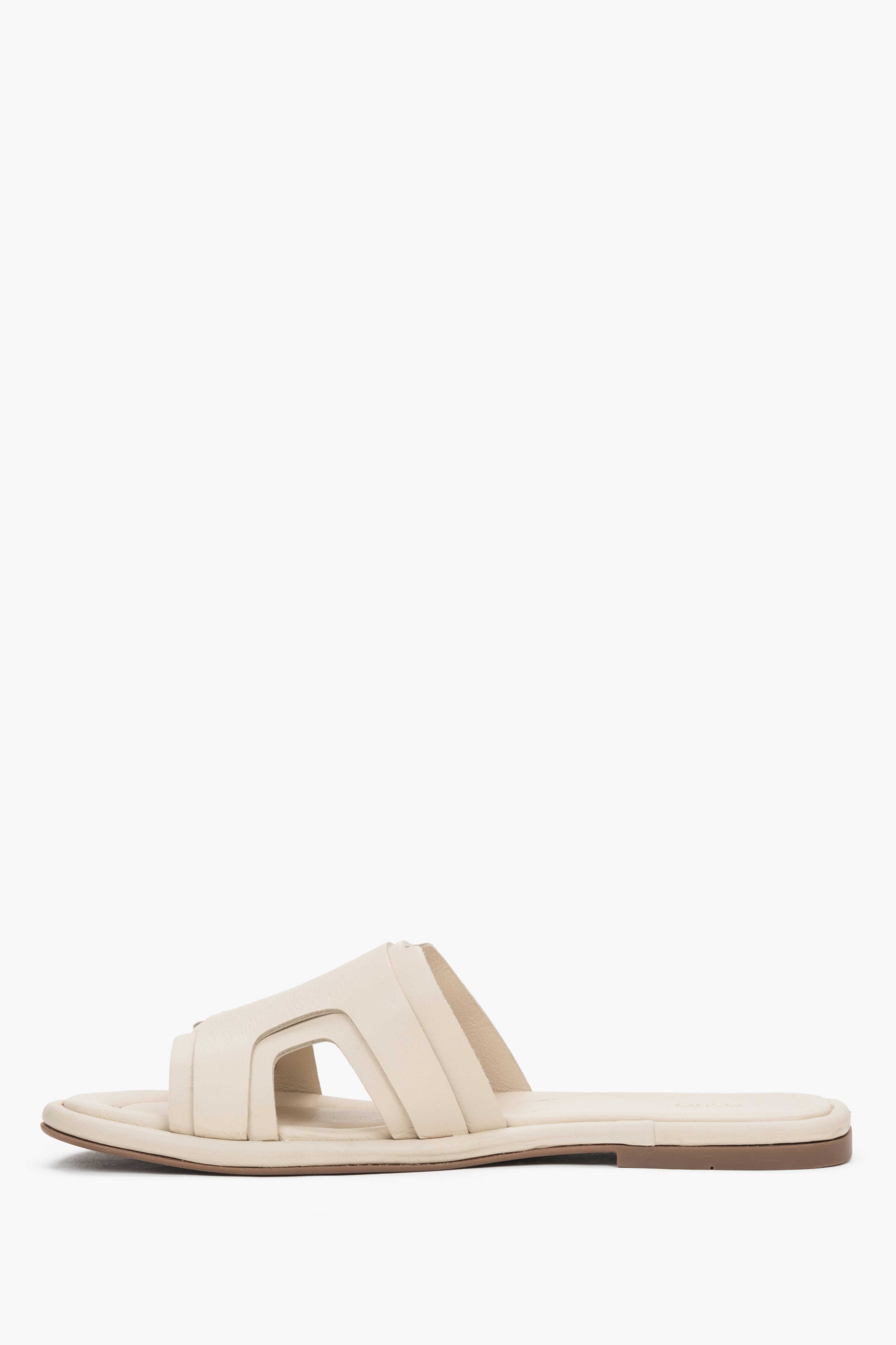 A profile shot of the beige leather slides highlighting the flat, flexible TPU sole and the comfortable, wide strap construction.