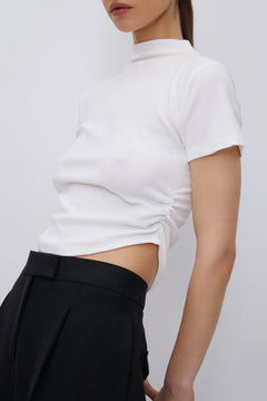 Close-up of gathered waist detail on milky beige T-shirt.