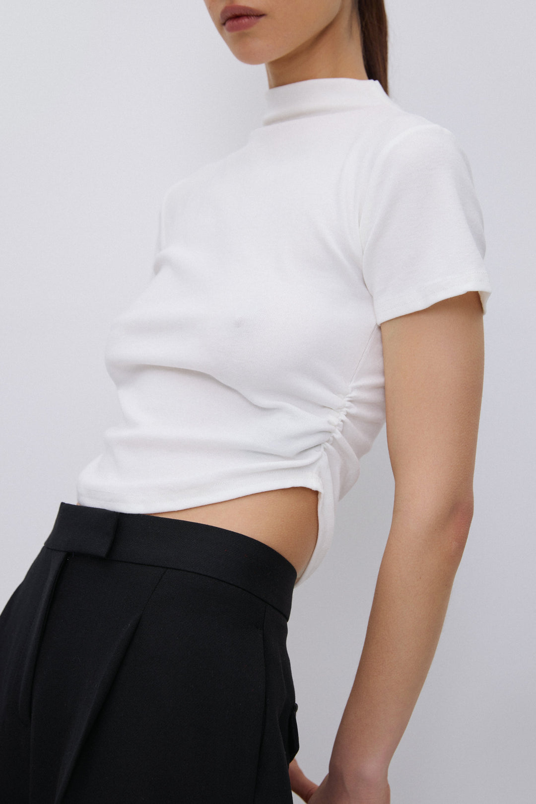 Close-up of gathered waist detail on milky beige T-shirt.
