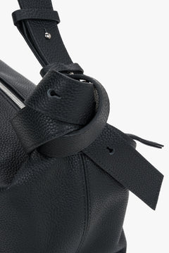 Women's black leather handbag Estro - close-up view focusing on the rich leather grain and decorative knot accent on the shoulder strap.