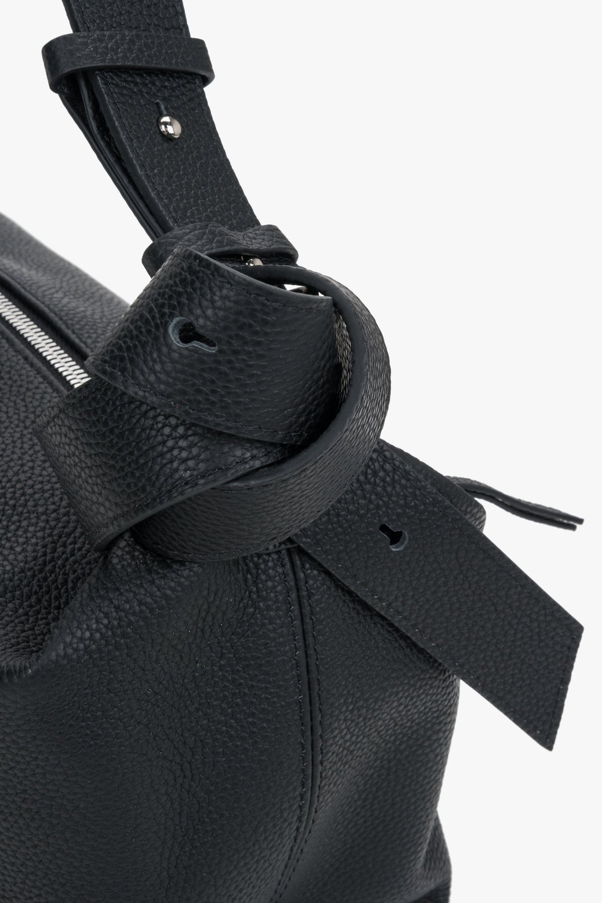 Women's black leather handbag Estro - close-up view focusing on the rich leather grain and decorative knot accent on the shoulder strap.