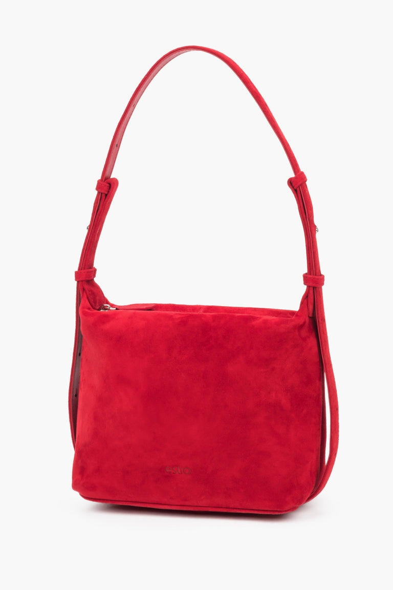 A red velvet Estro handbag with soft lines and a geometric design, showcasing the rich hue of the upper and a discreet logo.