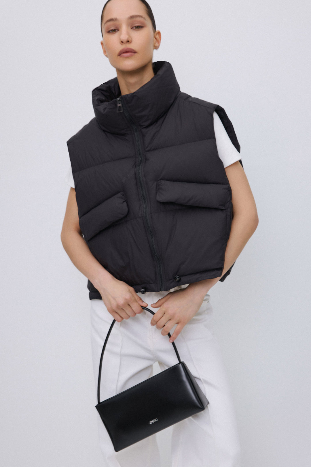 Short black women's puffer vest with zipper.