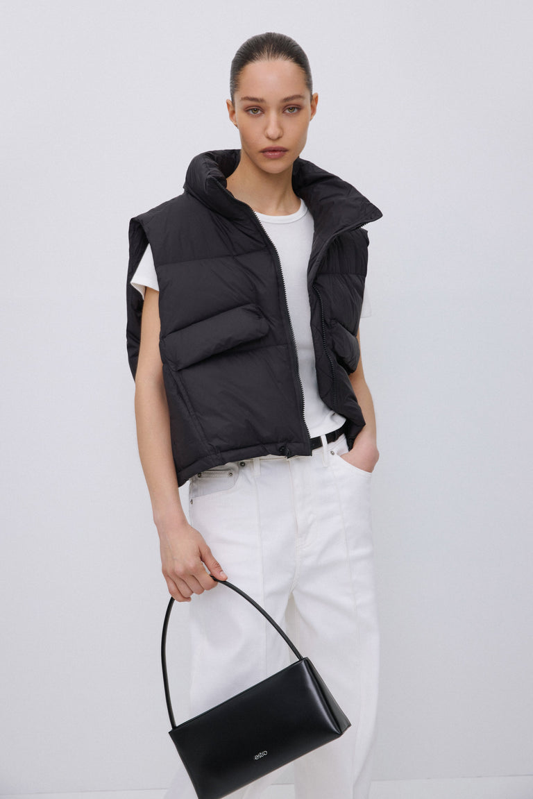 Model wearing short black down vest with zipper.
