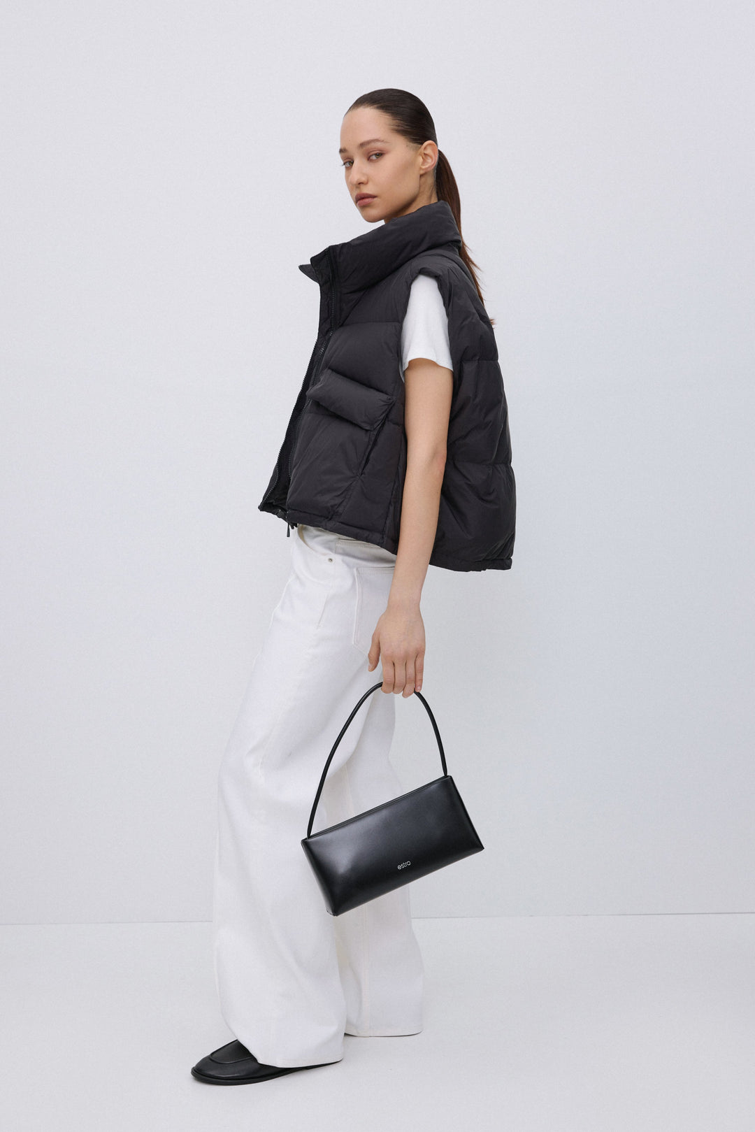 Side profile of black short quilted vest.