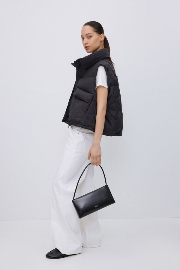 Side profile of black short quilted vest.