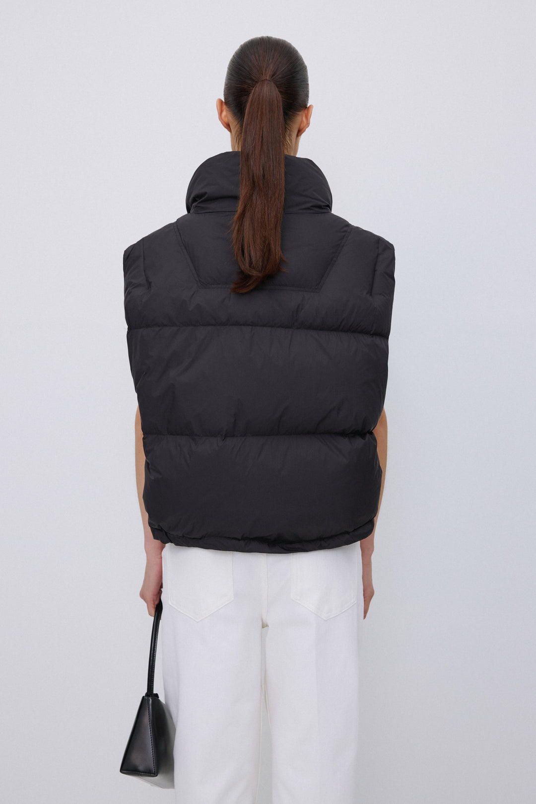 Back of women's short black puffer vest.