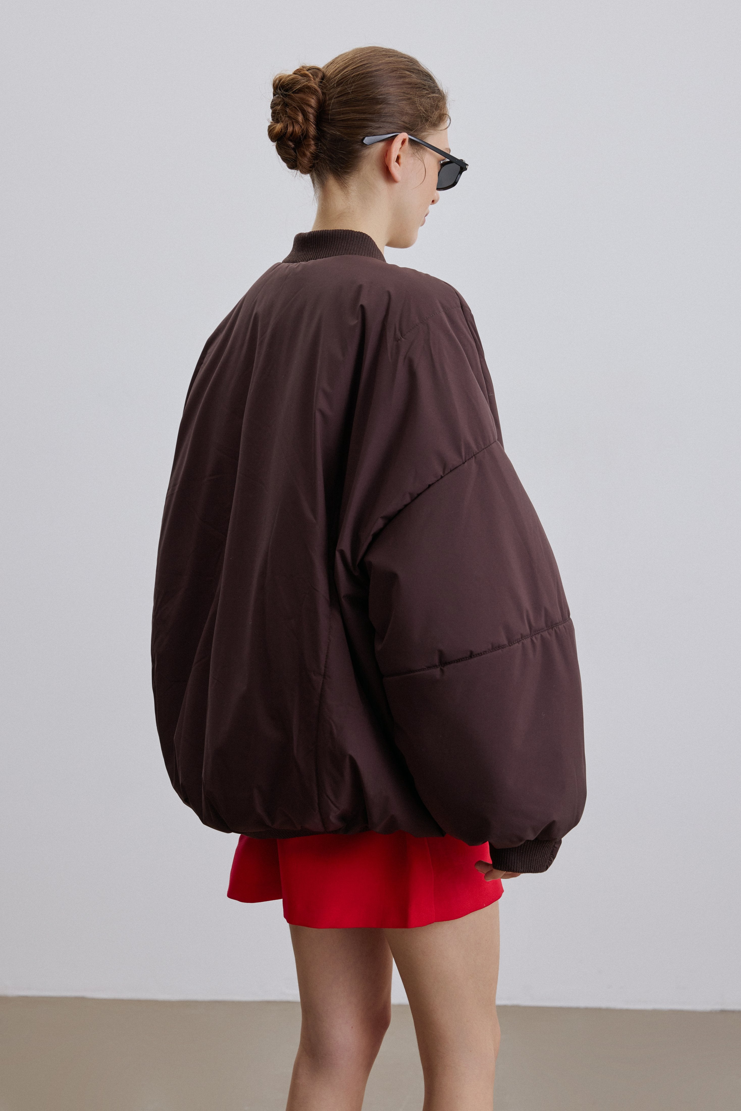 Front view of the dark brown oversize bomber jacket with stand collar.