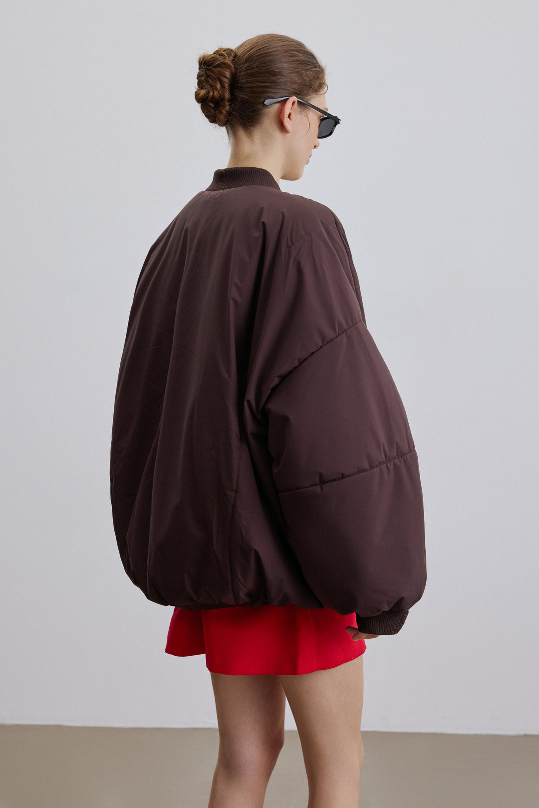 Front view of the dark brown oversize bomber jacket with stand collar.