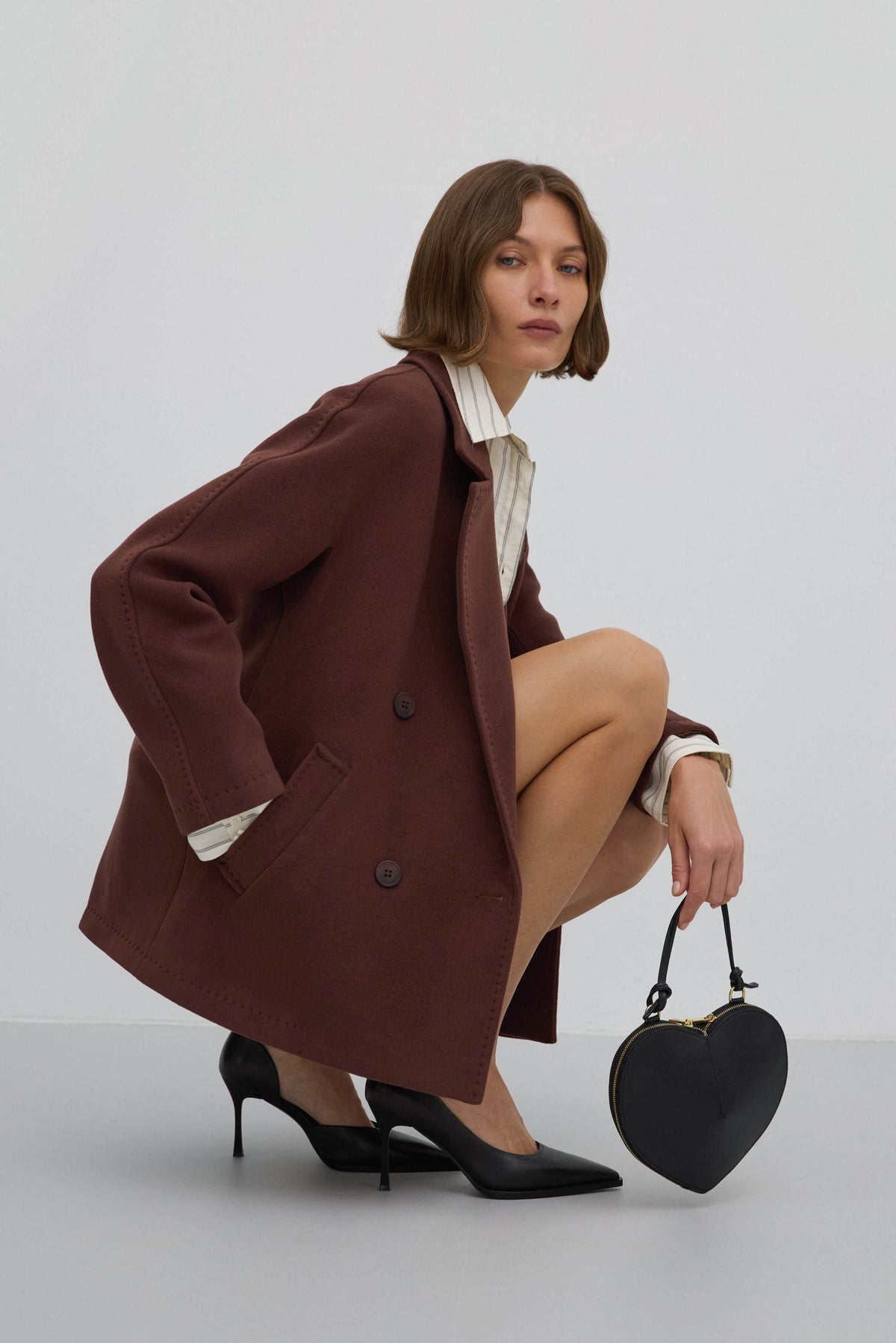 A short, dark brown, double-breasted women's coat made of wool by Estro.