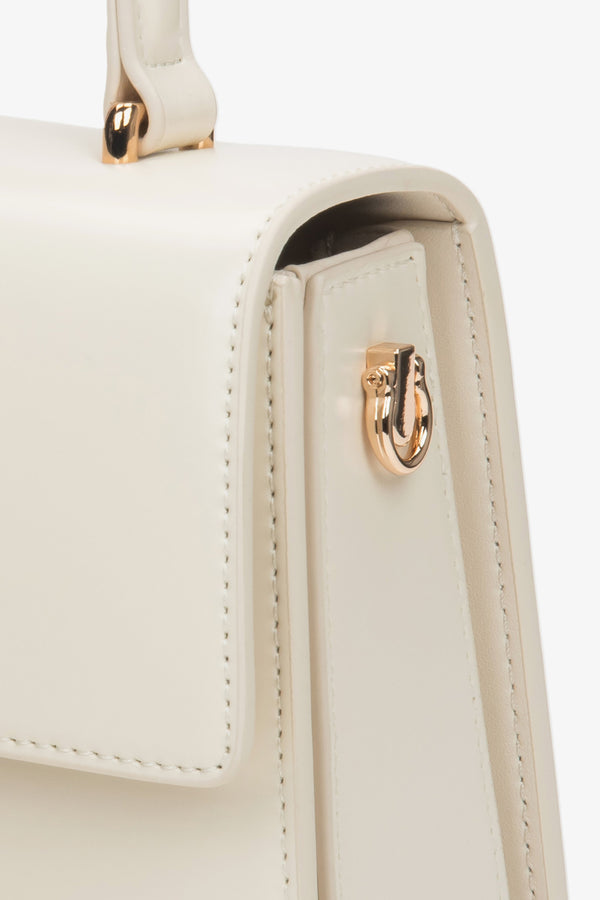 Compact and structured milky beige leather satchel, perfect for elegant formal styling.