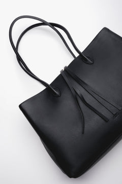 Black leather tote bag with a stylish drawstring puller at the zippers. Functionality and elegance in one.