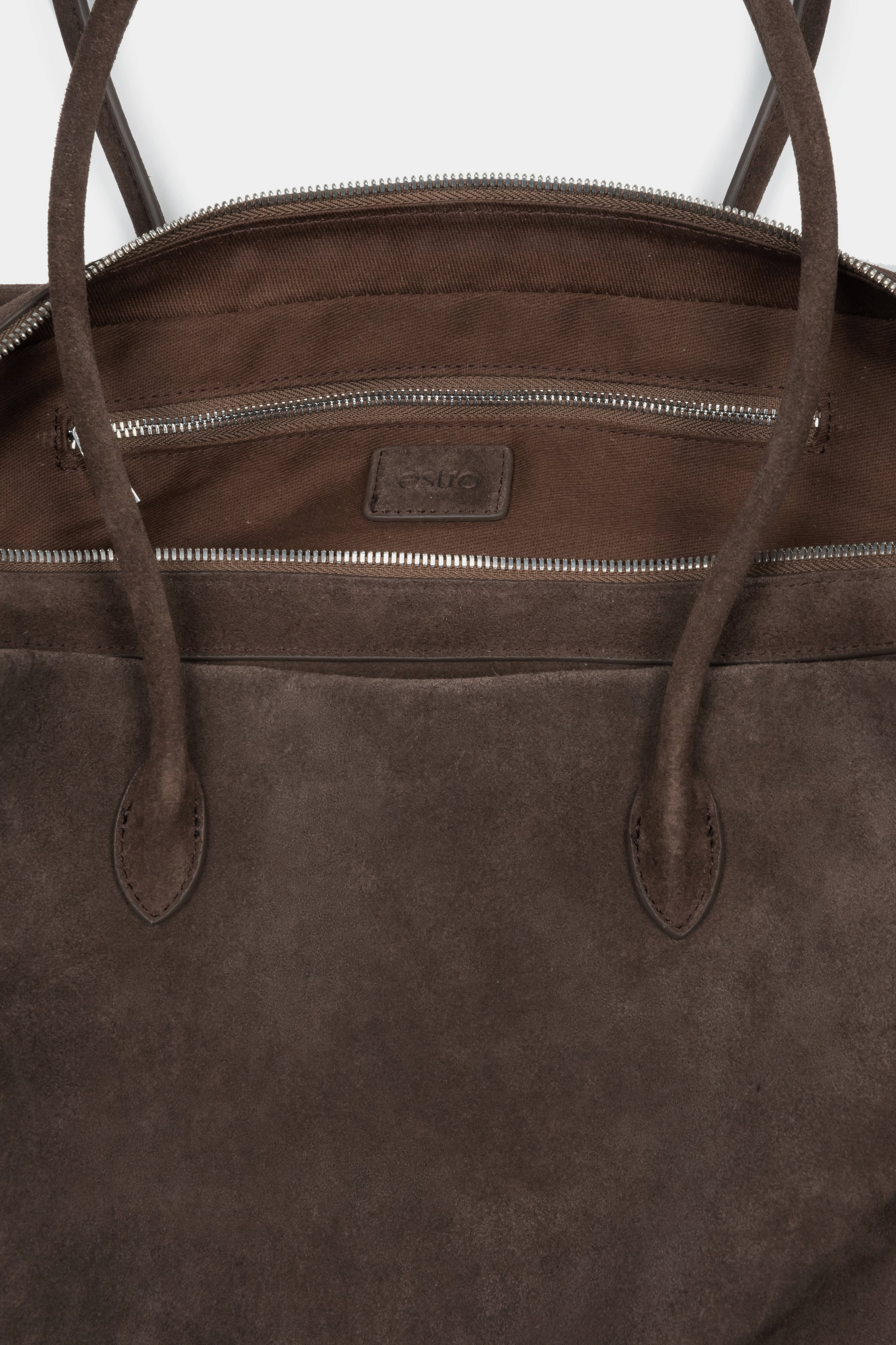 Close-up of the rich natural velour texture and zipper details on a dark brown bag.