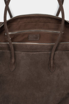 Close-up of the rich natural velour texture and zipper details on a dark brown bag.