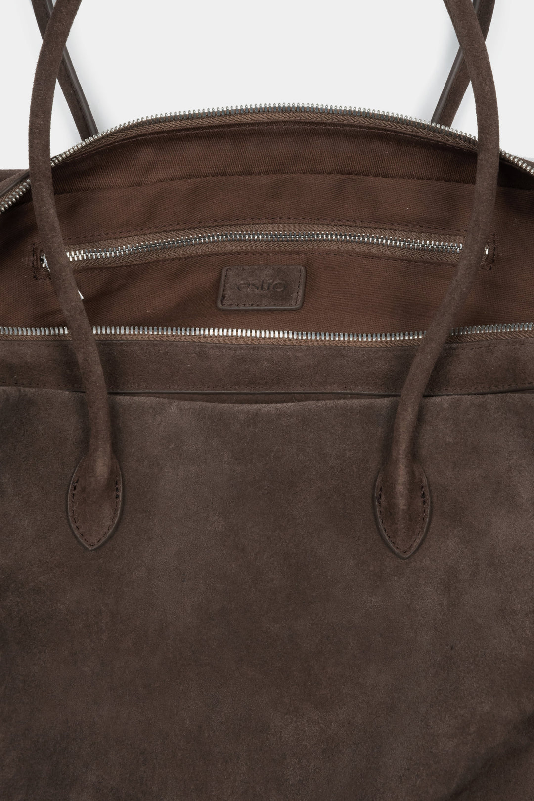 Close-up of the rich natural velour texture and zipper details on a dark brown bag.