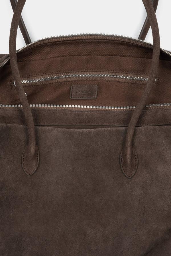 Close-up of the rich natural velour texture and zipper details on a dark brown bag.