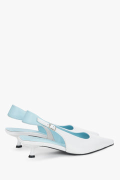 Detail view of the blue strap and buckle on white leather kitten heels.