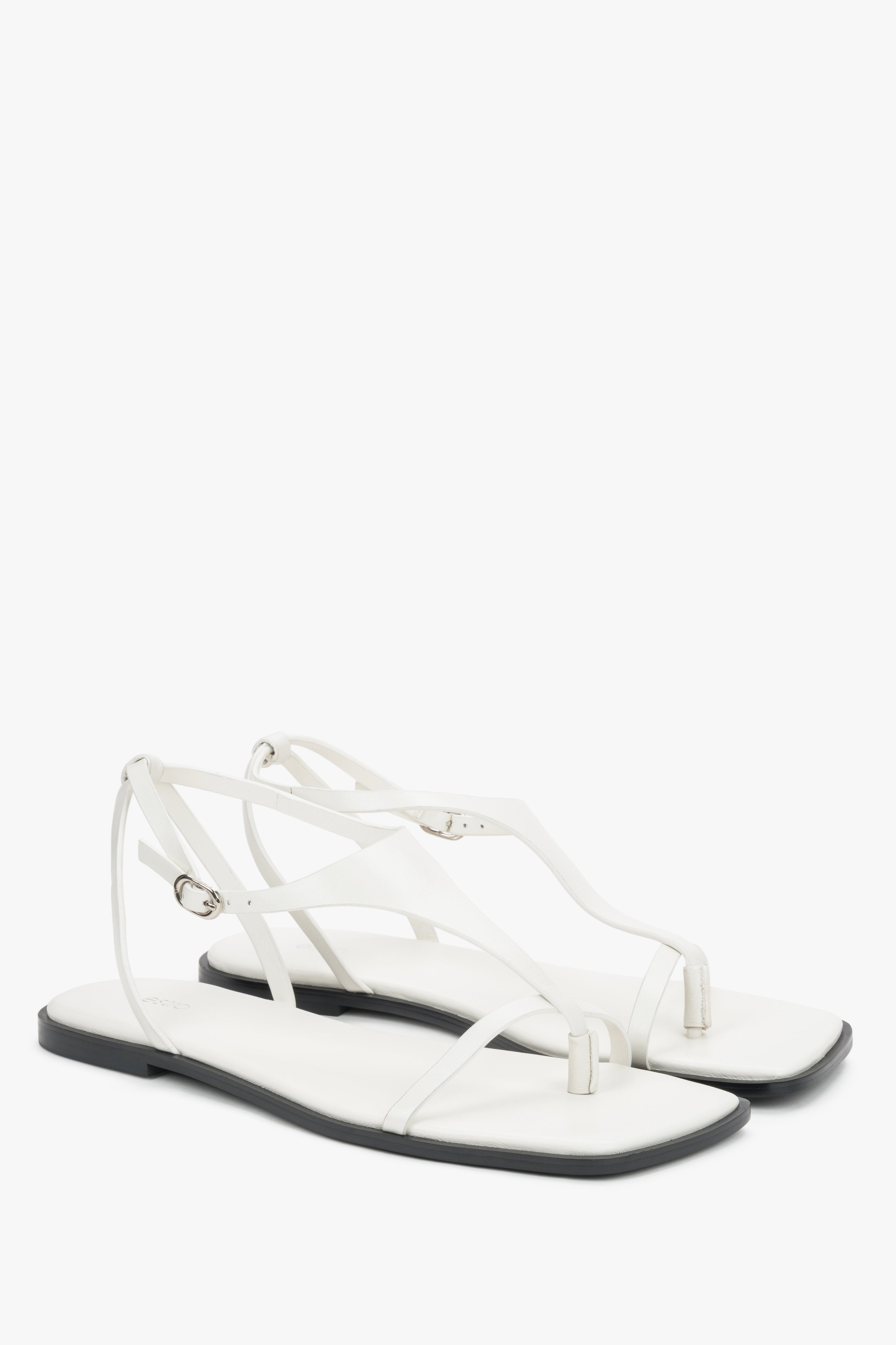 White flat sandals with a square toe and a toe-post strap.