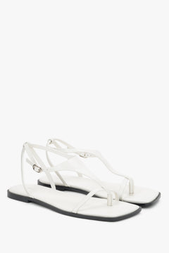 White flat sandals with a square toe and a toe-post strap.