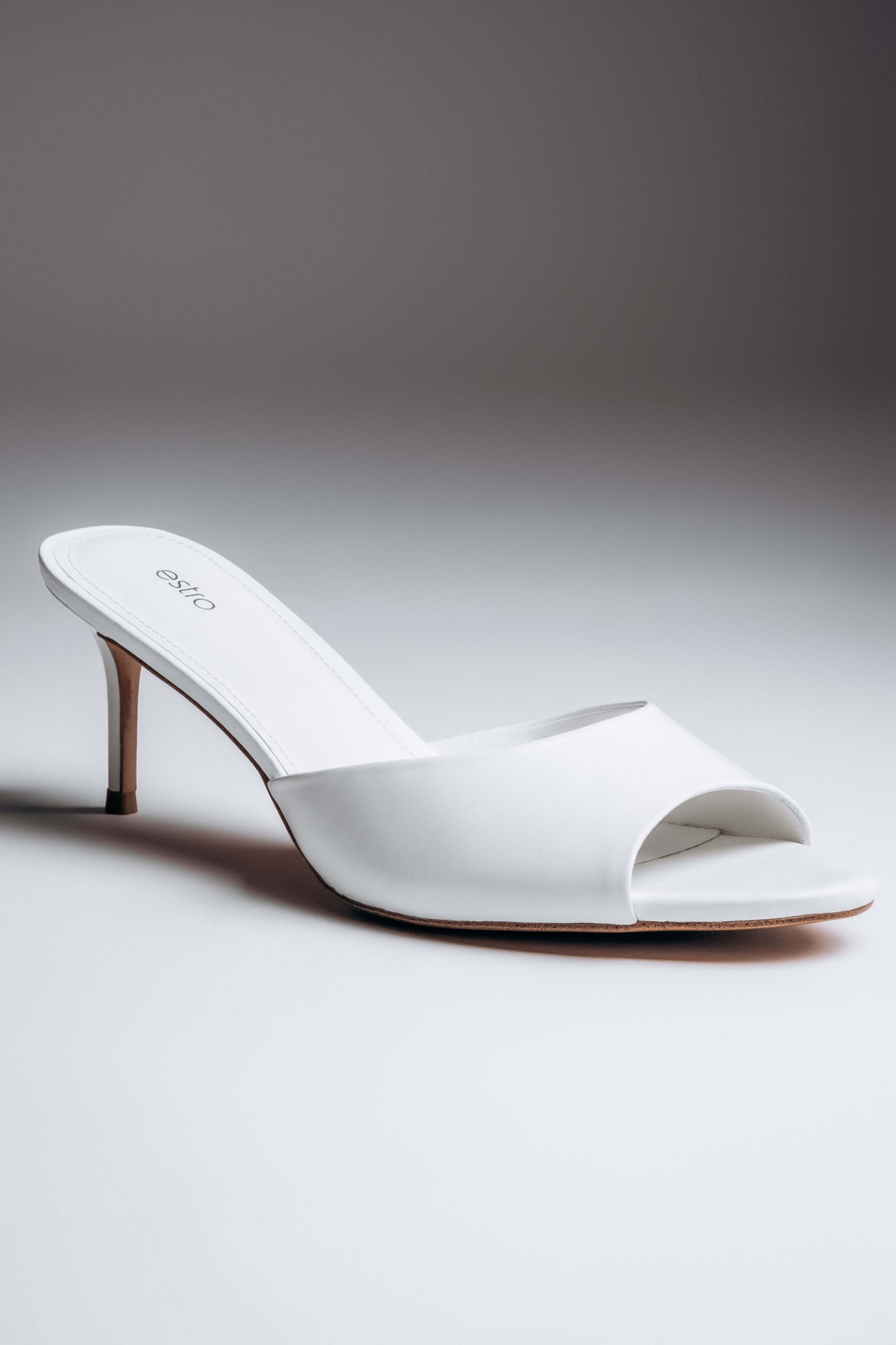 Close-up view of women's white leather mules with open toe