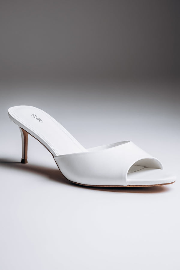 Close-up view of women's white leather mules with open toe
