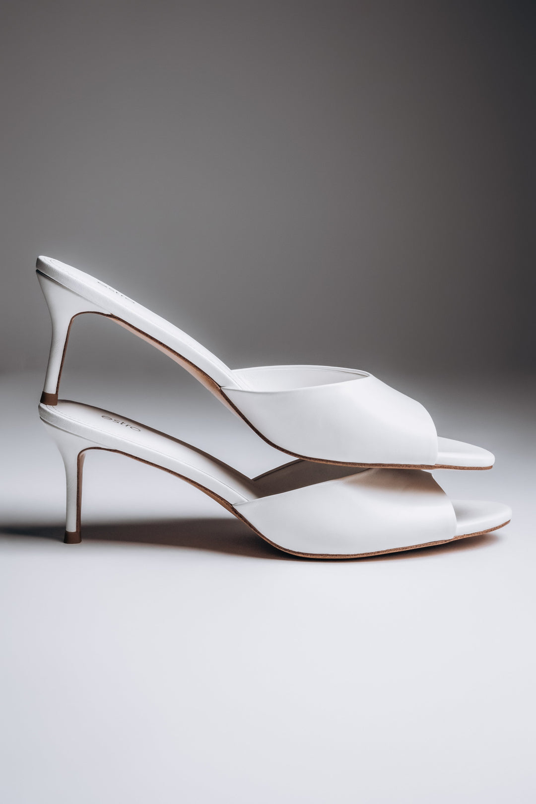 Side view of women's white leather mules with slim heel and open toe