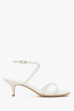 Elegant white leather sandals featuring criss-cross straps and a modern architectural heel.