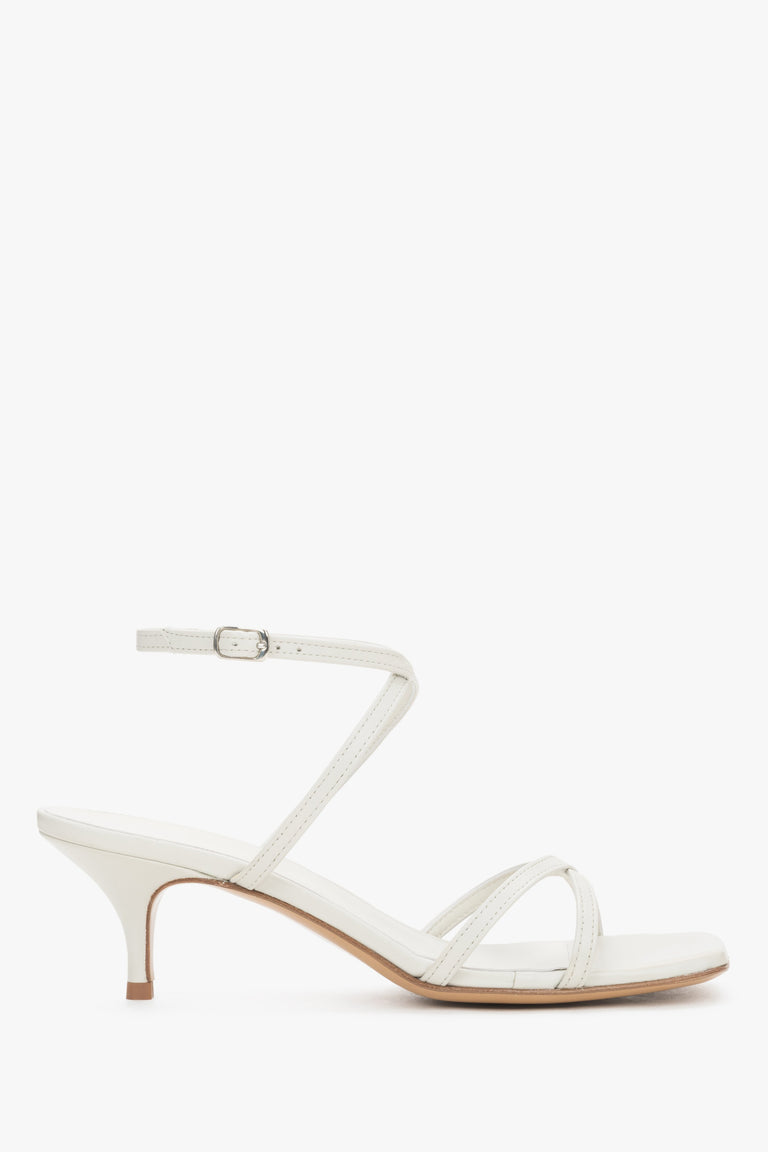 Elegant white leather sandals featuring criss-cross straps and a modern architectural heel.