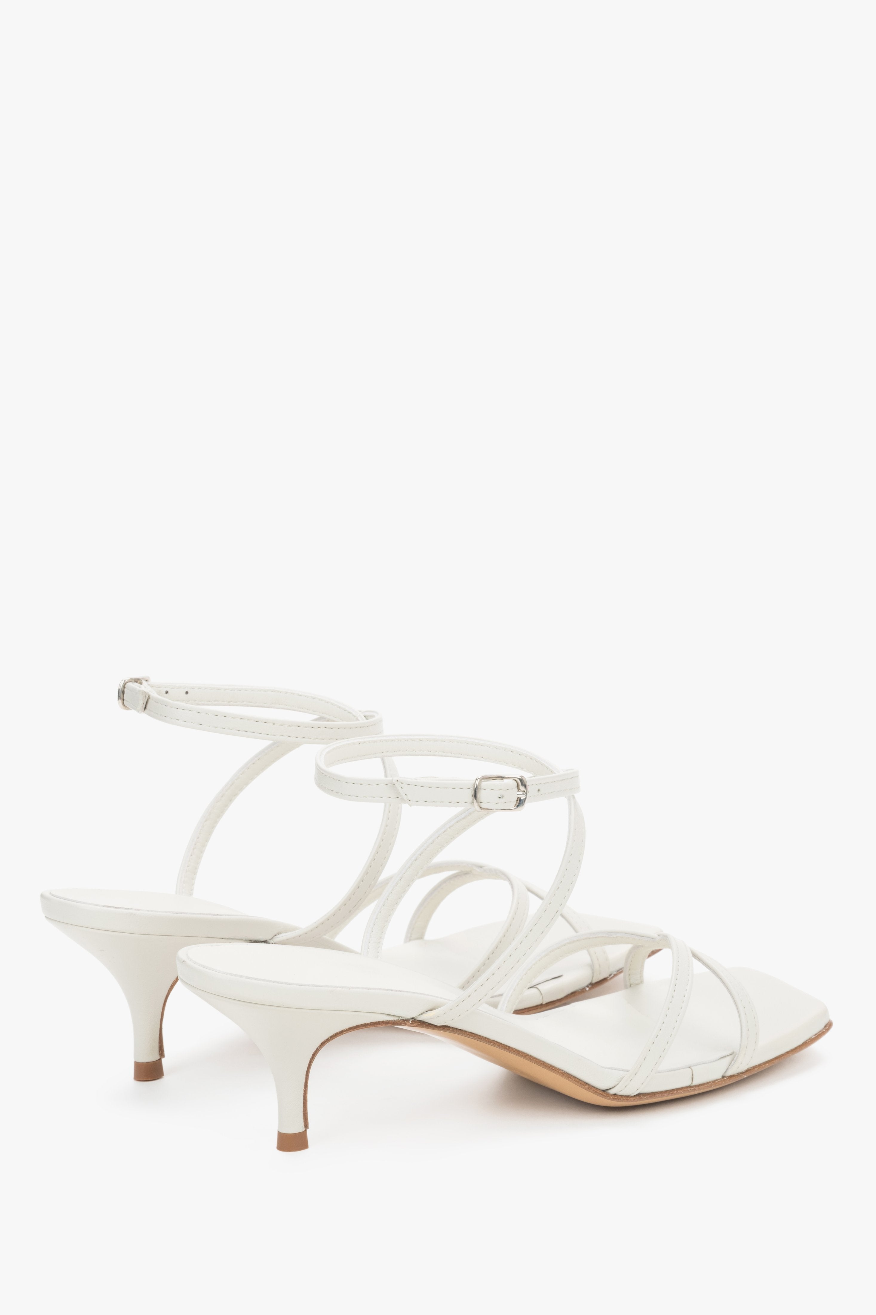 Close-up of the pristine white leather criss-crossing straps and stable flare heel.