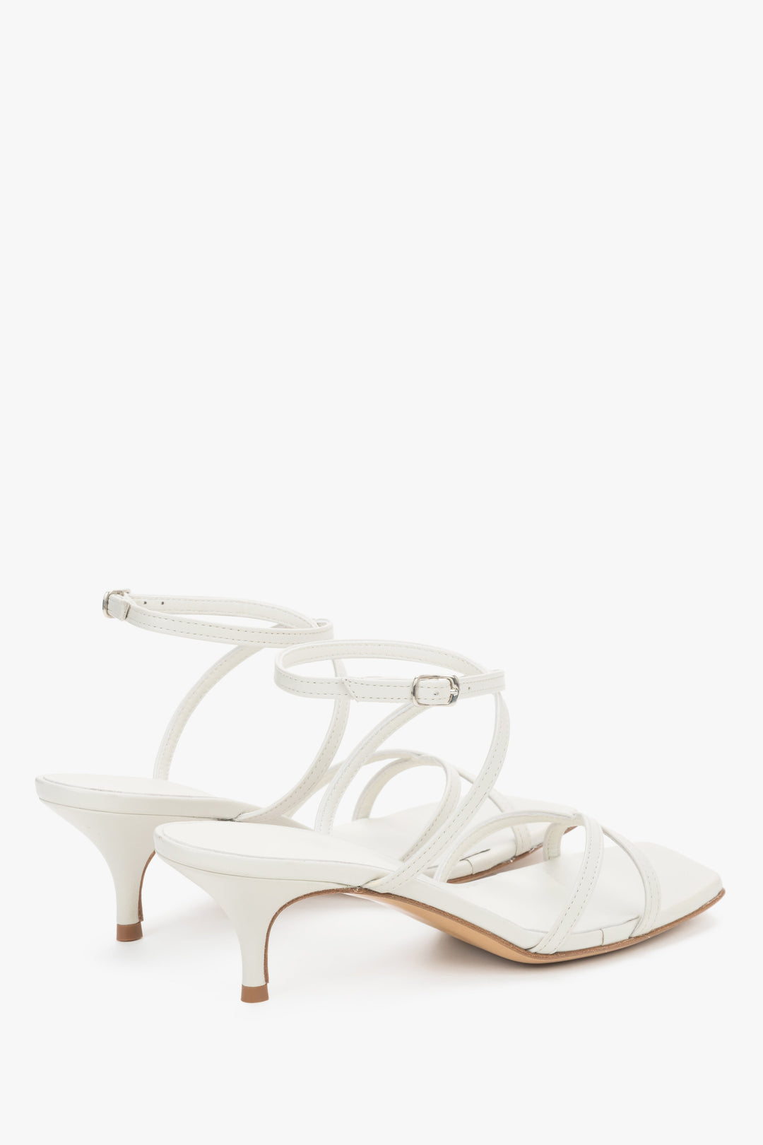 Close-up of the pristine white leather criss-crossing straps and stable flare heel.