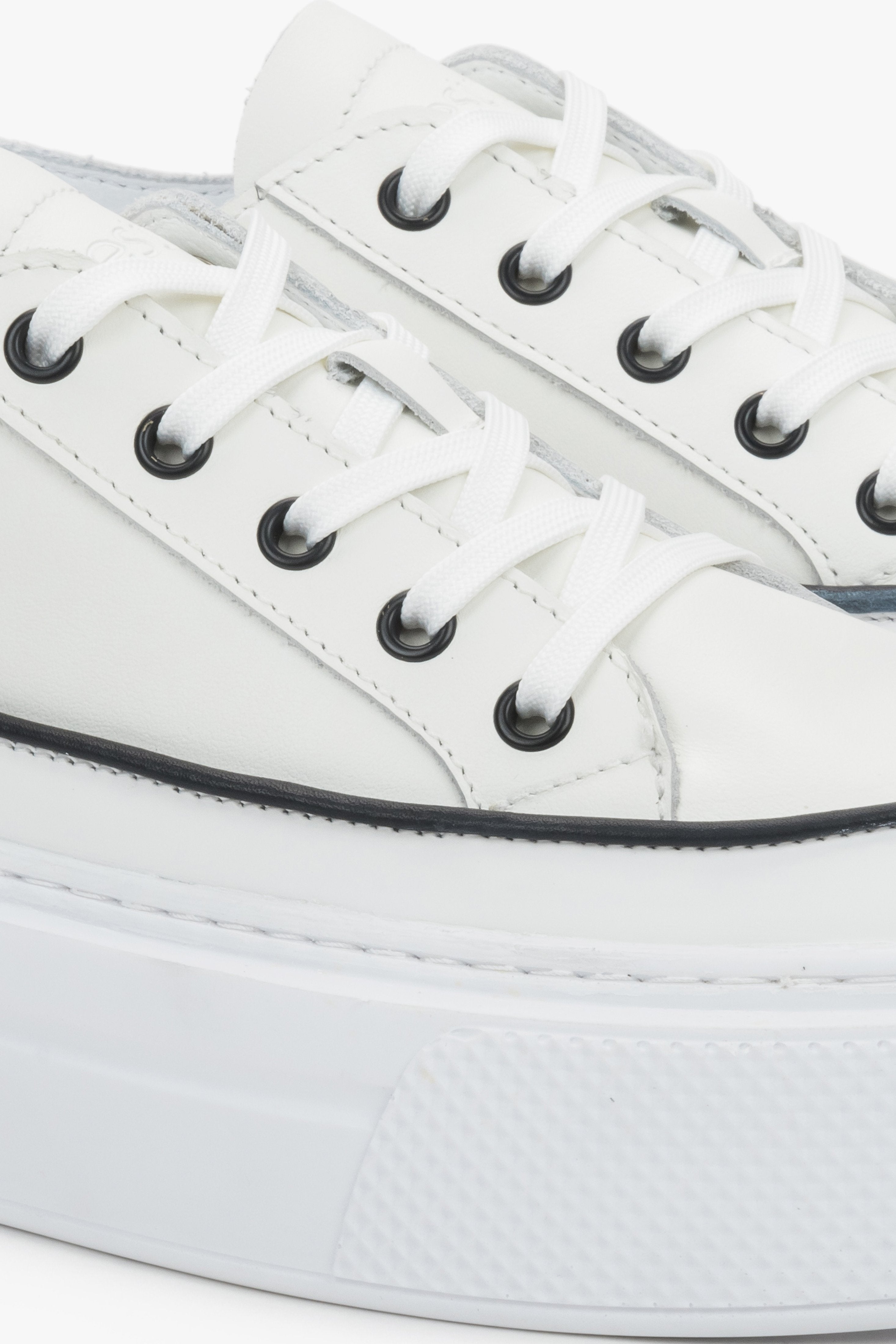 Detail view of the lace-up fastening and soft leather upper on white Estro sneakers.