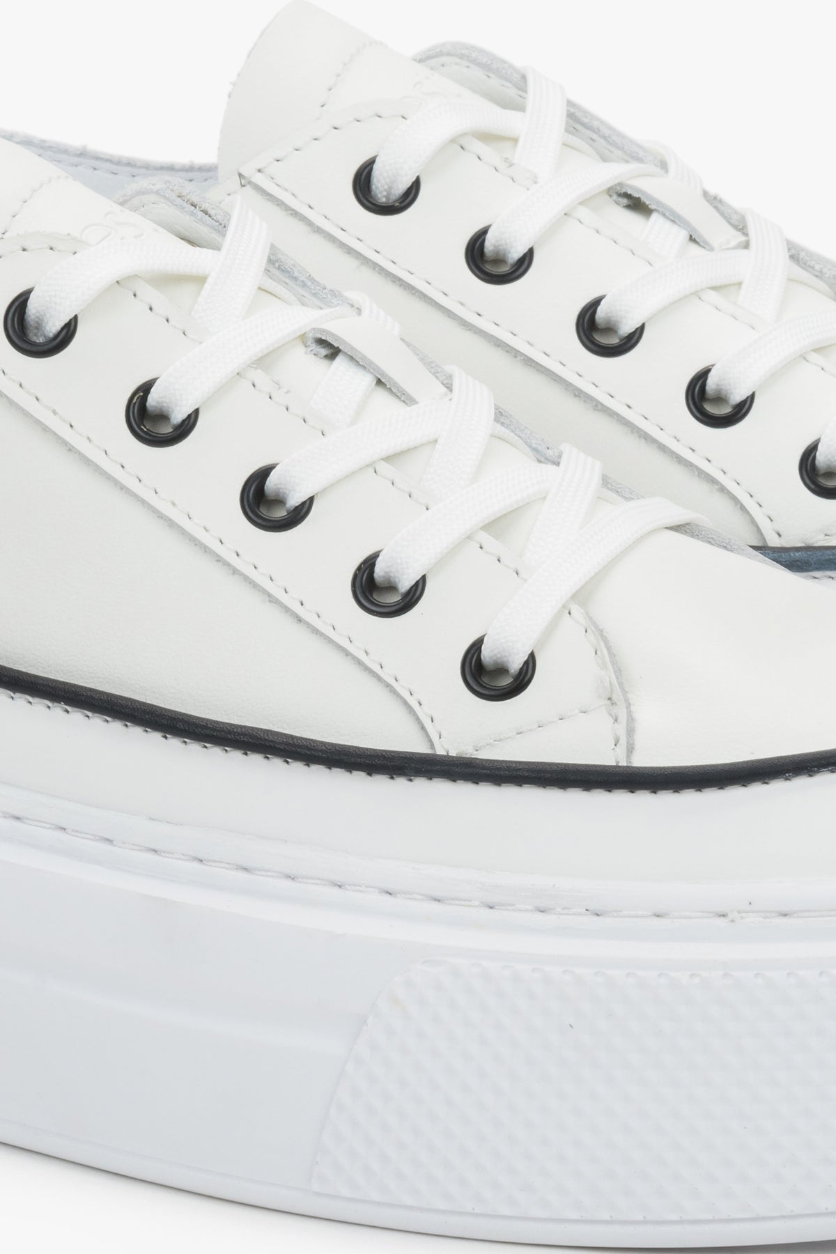 Detail view of the lace-up fastening and soft leather upper on white Estro sneakers.
