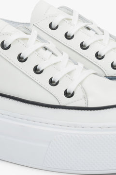 Detail view of the lace-up fastening and soft leather upper on white Estro sneakers.