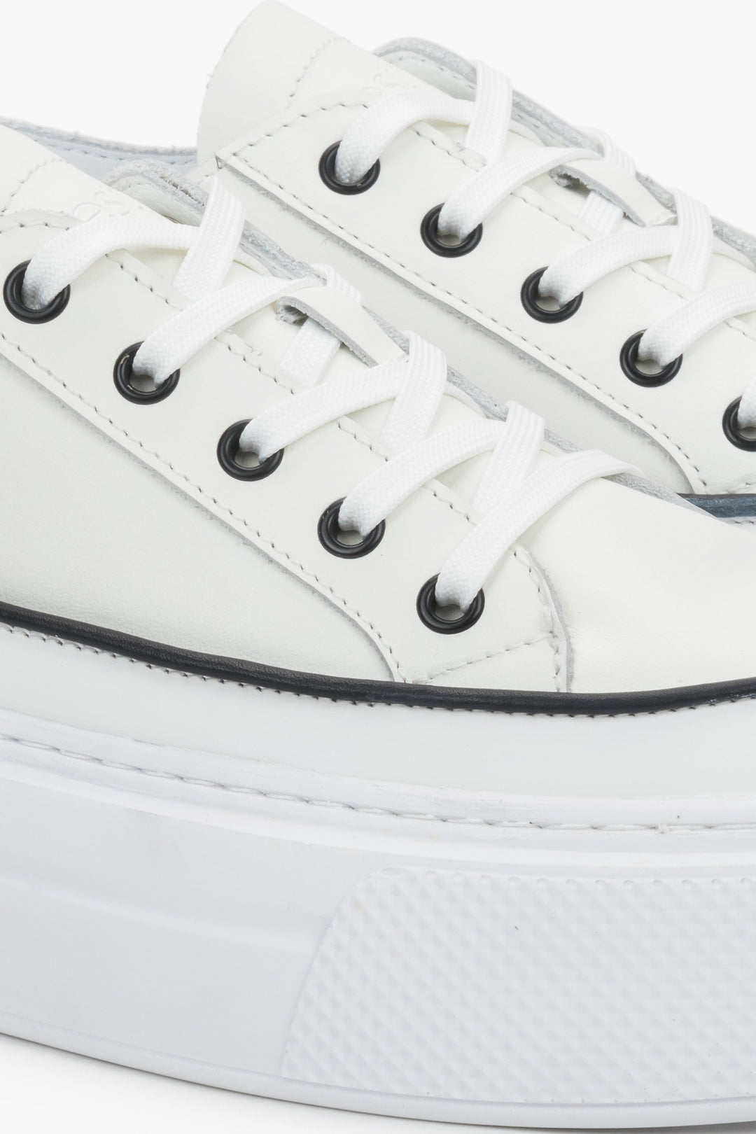 Detail view of the lace-up fastening and soft leather upper on white Estro sneakers.
