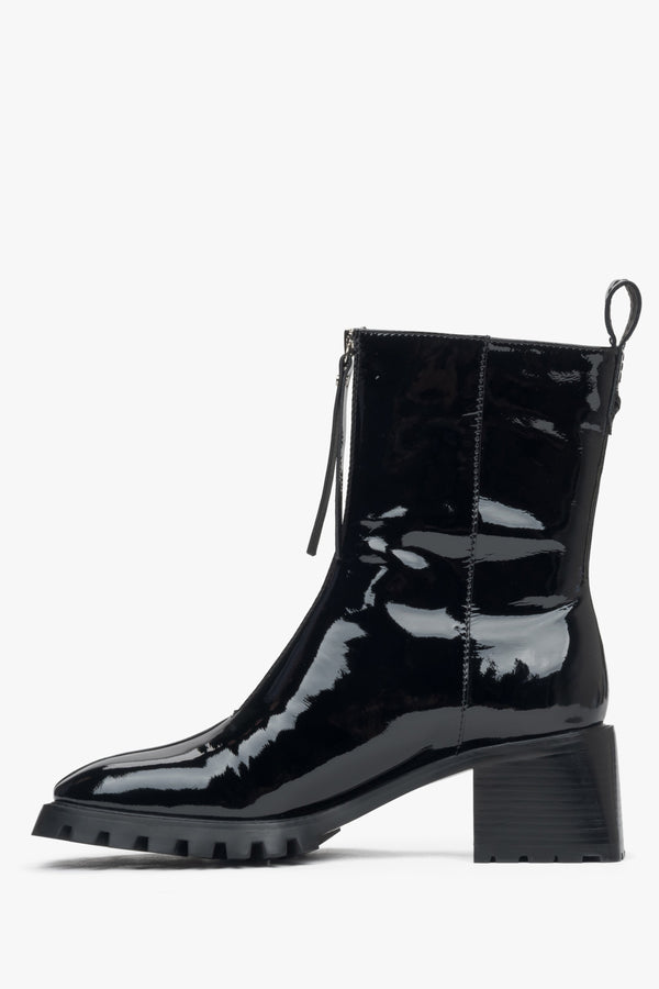 Stylish women's black ankle boots made of patent genuine leather with a low heel - side view of the shoe.