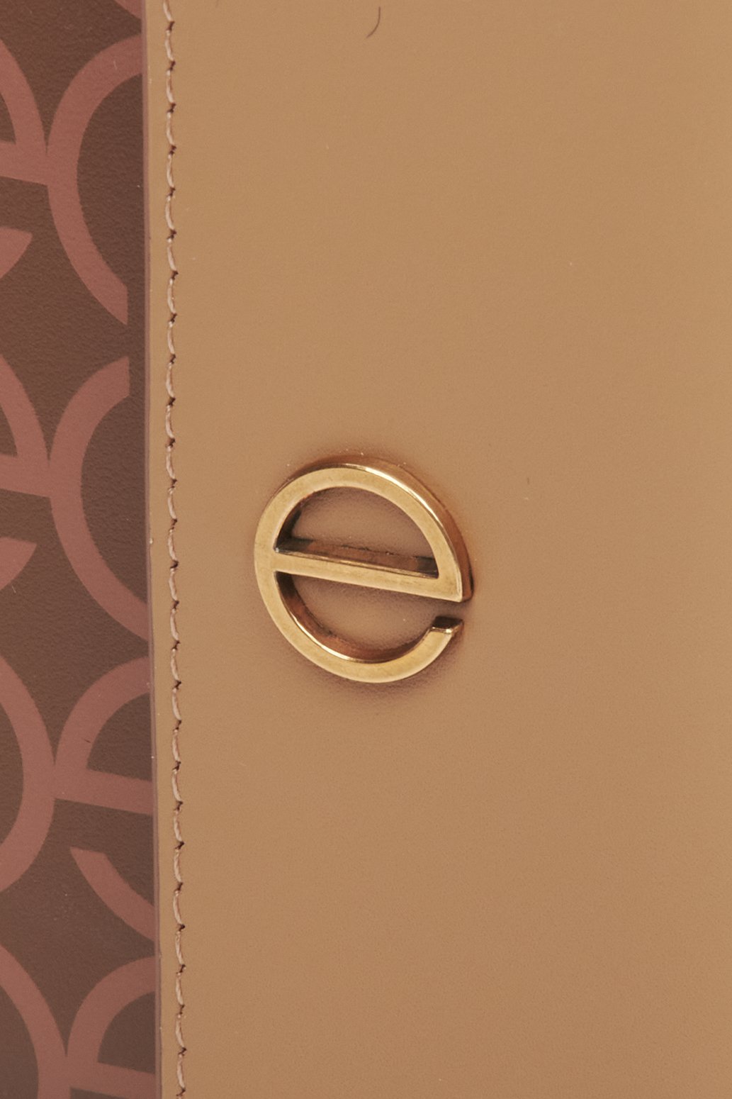 Women's leather tri-fold wallet with golden accents by Estro - close-up on the emblem.