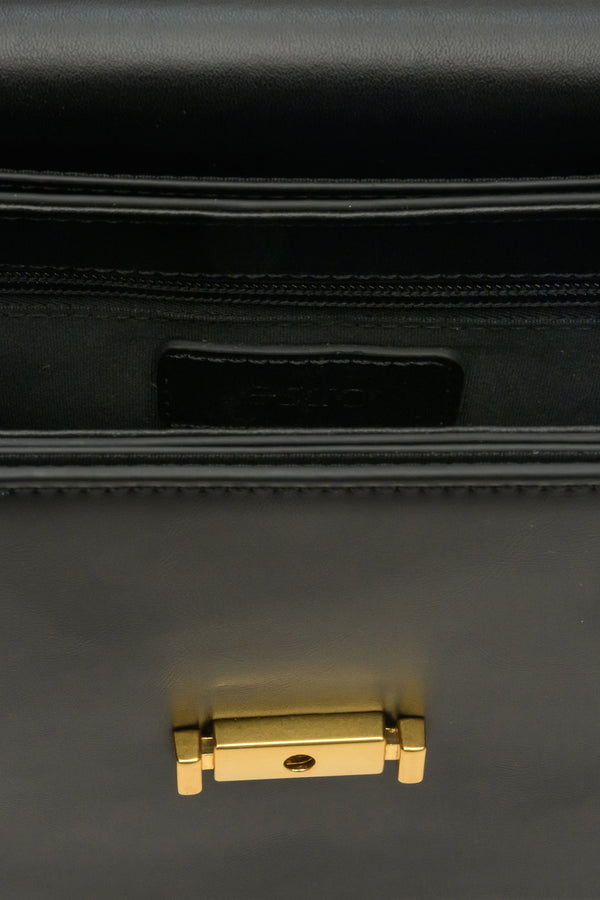 Small women's handbag made of genuine black leather with gold accents - close-up on details.